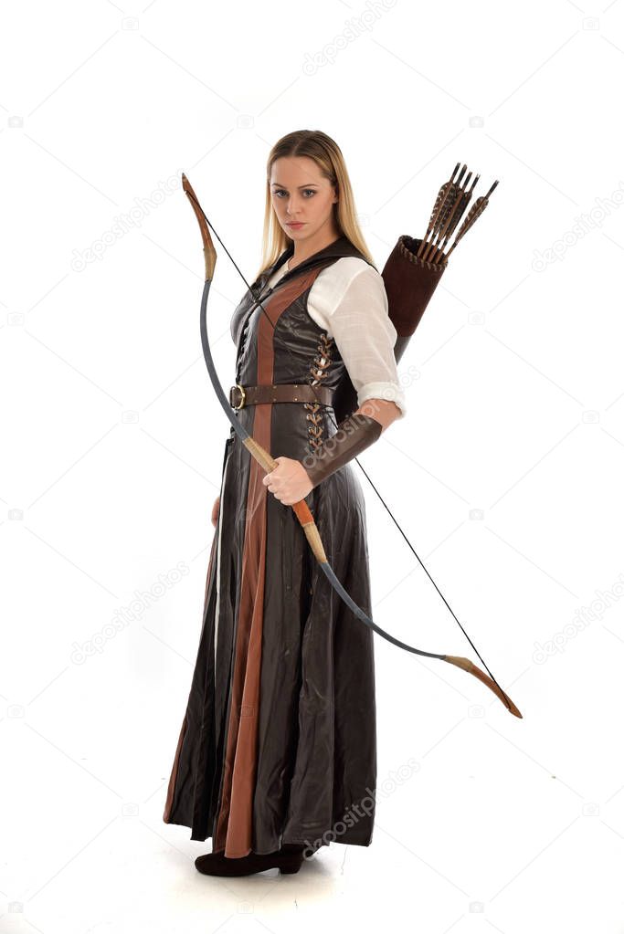 full length portrait of woman wearing brown medieval fantasy outfit, with a bow and arrow. standing pose on white studio background.