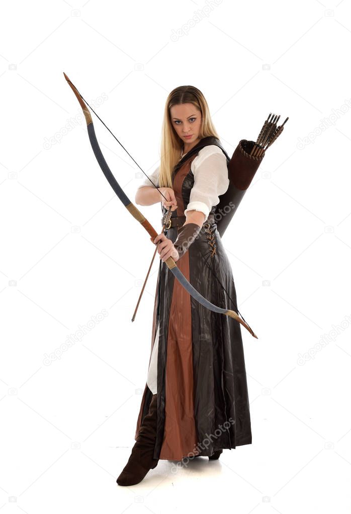 full length portrait of woman wearing brown medieval fantasy outfit, with a bow and arrow. standing pose on white studio background.