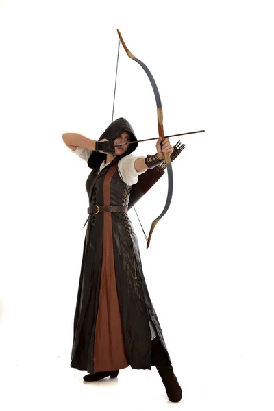 黒のマントで中世の射手の衣装を身に着けている赤い髪の少女の完全な長