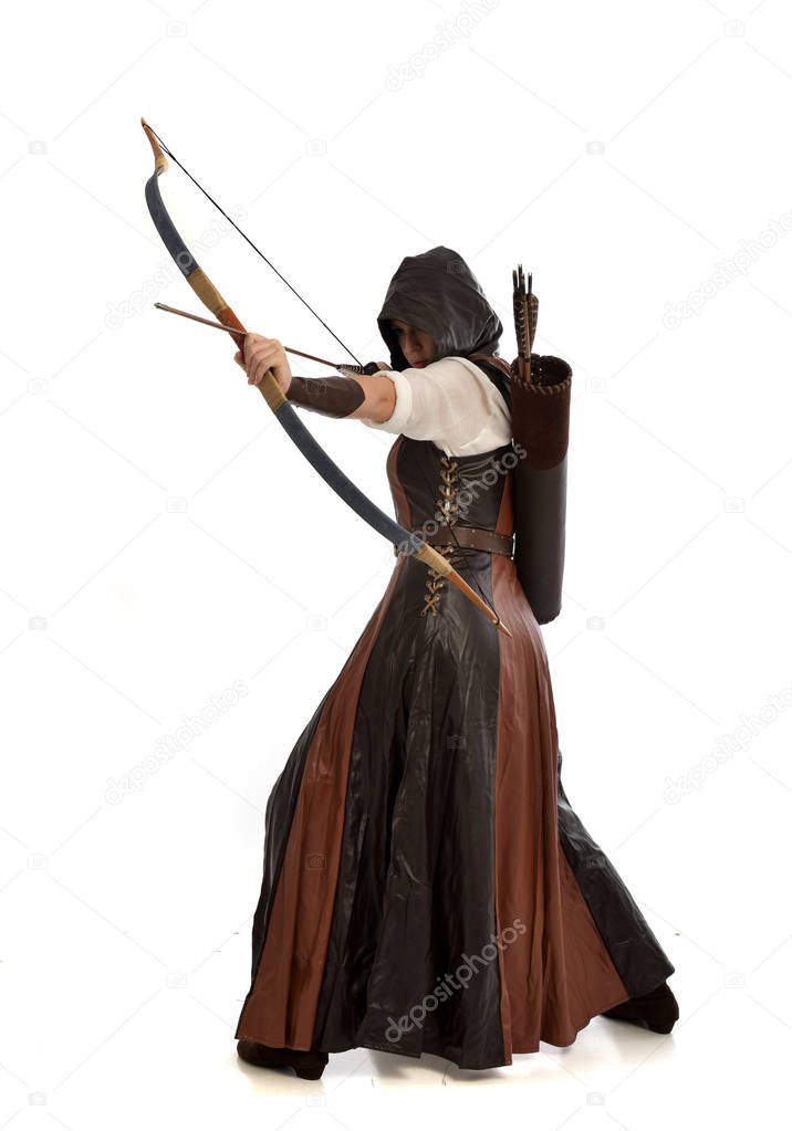 full length portrait of woman wearing brown medieval fantasy outfit, with a bow and arrow. standing pose on white studio background.