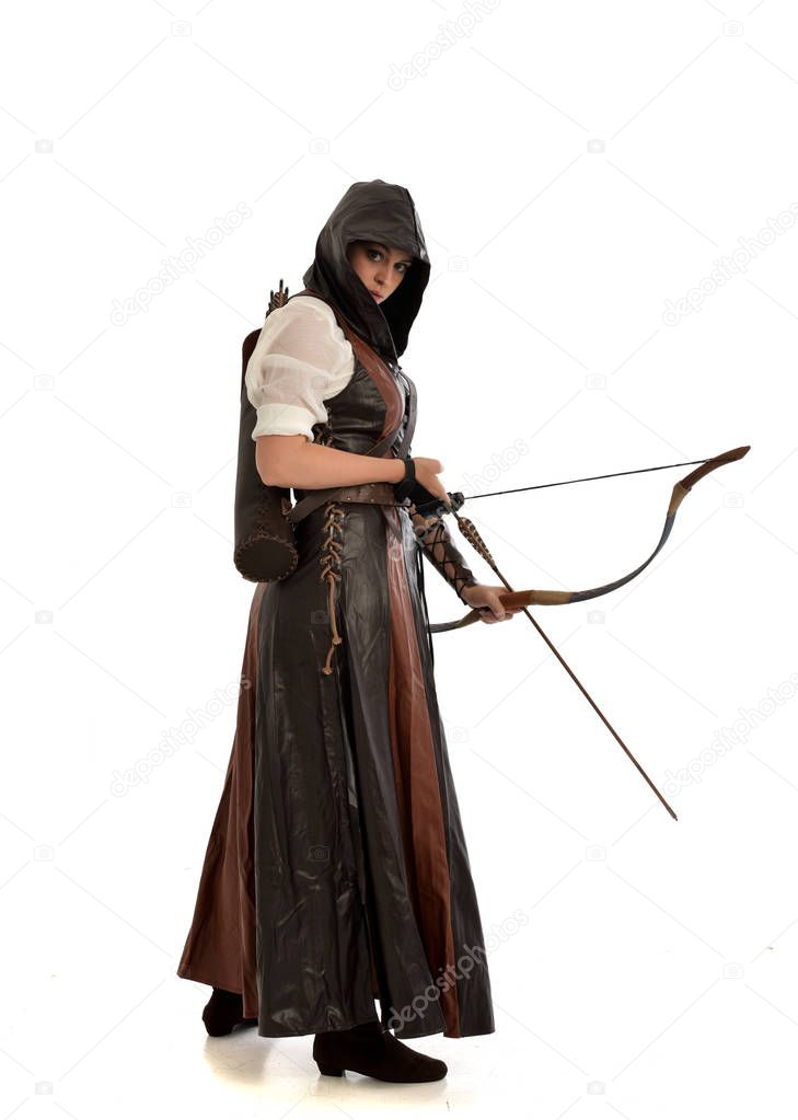 full length portrait of woman wearing brown medieval fantasy outfit, with a bow and arrow. standing pose on white studio background.