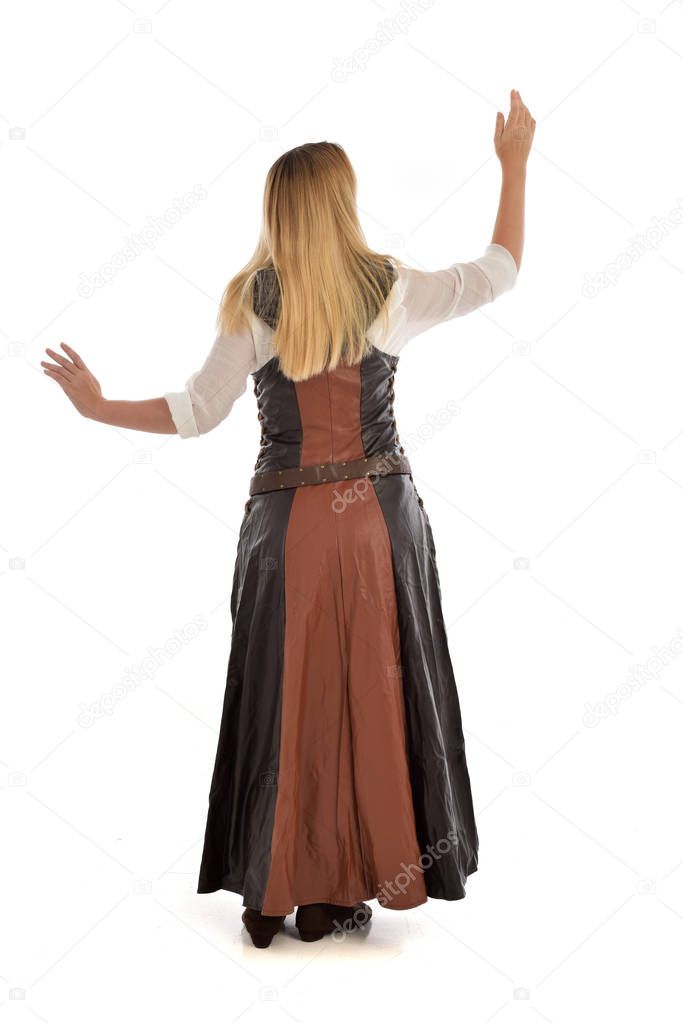 full length portrait of blonde girl wearing  brown leather fantasy outfit, standing pose with the back to the camera. isolated on white studio background.