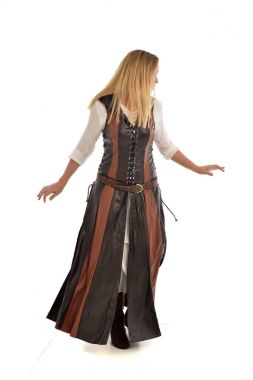 tam uzunlukta kahverengi deri fantezi kıyafeti, arkadaki kameraya pozuyla ayakta giymiş sarışın kız portresi. Beyaz stüdyo arka plan üzerinde izole.