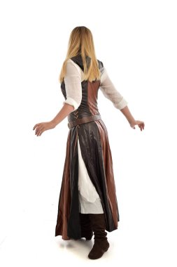 tam uzunlukta kahverengi deri fantezi kıyafeti, arkadaki kameraya pozuyla ayakta giymiş sarışın kız portresi. Beyaz stüdyo arka plan üzerinde izole.