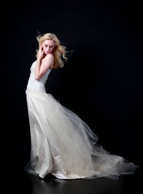 tam uzunlukta portre beyaz model giyen gelin topu cüppe, ayakta poz siyah arka plan üzerine.