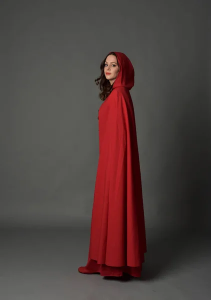 マント 灰色のスタジオの背景に立ちポーズで赤のファンタジー衣装を着てブルネットの女性の完全な長さの肖像画 — ストック写真