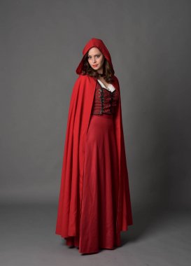 tam uzunlukta pelerin, ayakta poz gri studio arka plan üzerinde kırmızı fantezi Kostüm giymiş esmer Bayan portresi.