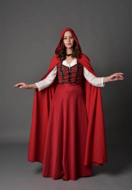 tam uzunlukta pelerin, ayakta poz gri studio arka plan üzerinde kırmızı fantezi Kostüm giymiş esmer Bayan portresi.