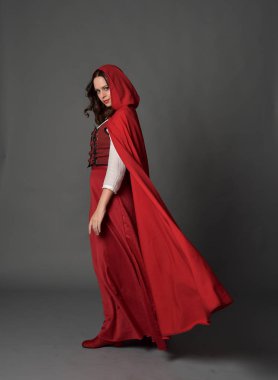 tam uzunlukta pelerin, ayakta poz gri studio arka plan üzerinde kırmızı fantezi Kostüm giymiş esmer Bayan portresi.