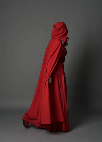 マント 灰色のスタジオの背景に立ちポーズで赤のファンタジー衣装を着てブルネットの女性の完全な長さの肖像画 — ストック写真