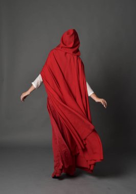 full length portrait of brunette lady wearing red fantasy costume with cloak, standing pose on grey studio background. clipart