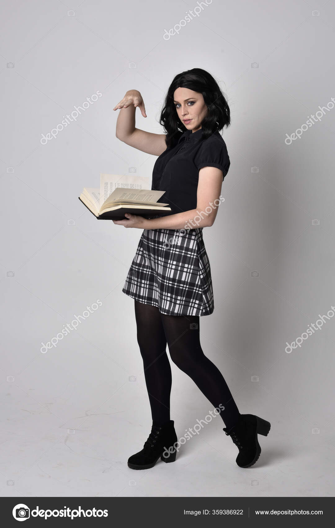 一个黑头发的哥特女孩穿着蓝色格子呢裙和靴子的画像全长站立姿势手持一本书在工作室的背景下 图库照片 C Faestock 一个黑头发的哥特女孩穿着蓝色格子呢裙和靴子的画像全长站立姿势手持一本书在工作室的背景下 图库照片 C Faestock