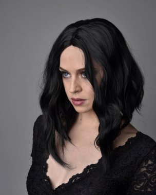 Stüdyo arka planında poz veren siyah saçlı güzel, gotik bir kızın yakın portresi..