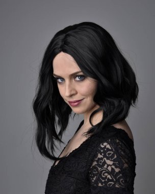 Stüdyo arka planında poz veren siyah saçlı güzel, gotik bir kızın yakın portresi..