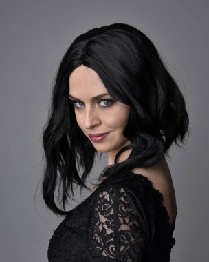 Stüdyo arka planında poz veren siyah saçlı güzel, gotik bir kızın yakın portresi..