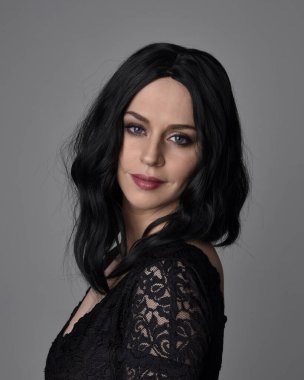 Stüdyo arka planında poz veren siyah saçlı güzel, gotik bir kızın yakın portresi..