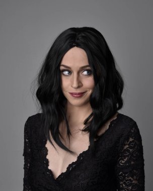 Stüdyo arka planında poz veren siyah saçlı güzel, gotik bir kızın yakın portresi..