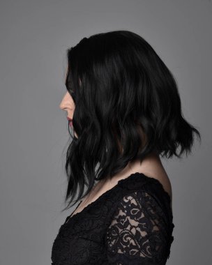 Stüdyo arka planında poz veren siyah saçlı güzel, gotik bir kızın yakın portresi..