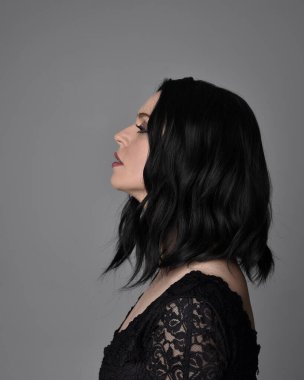 Stüdyo arka planında poz veren siyah saçlı güzel, gotik bir kızın yakın portresi..