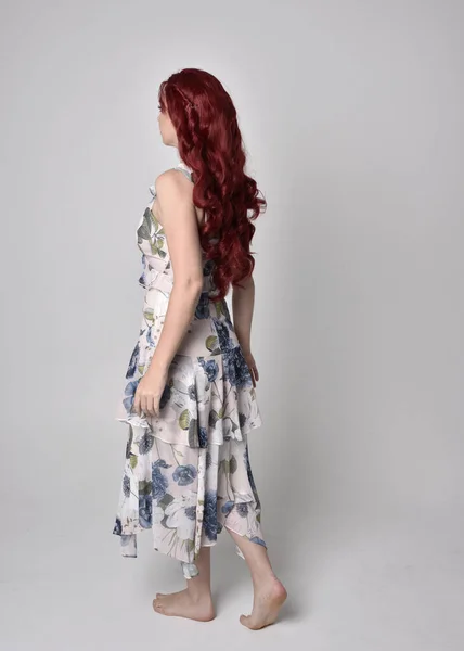 一个红头发的漂亮女人穿着飘逸的花衣的画像 全长站立姿势 与工作室背景隔离 — 图库照片