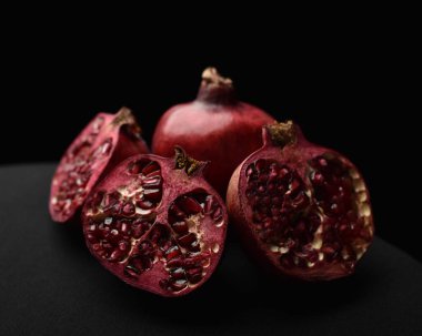 Bir meyvenin kapanışı natürmorttur, siyah bir stüdyonun arka planında nar kesilir..