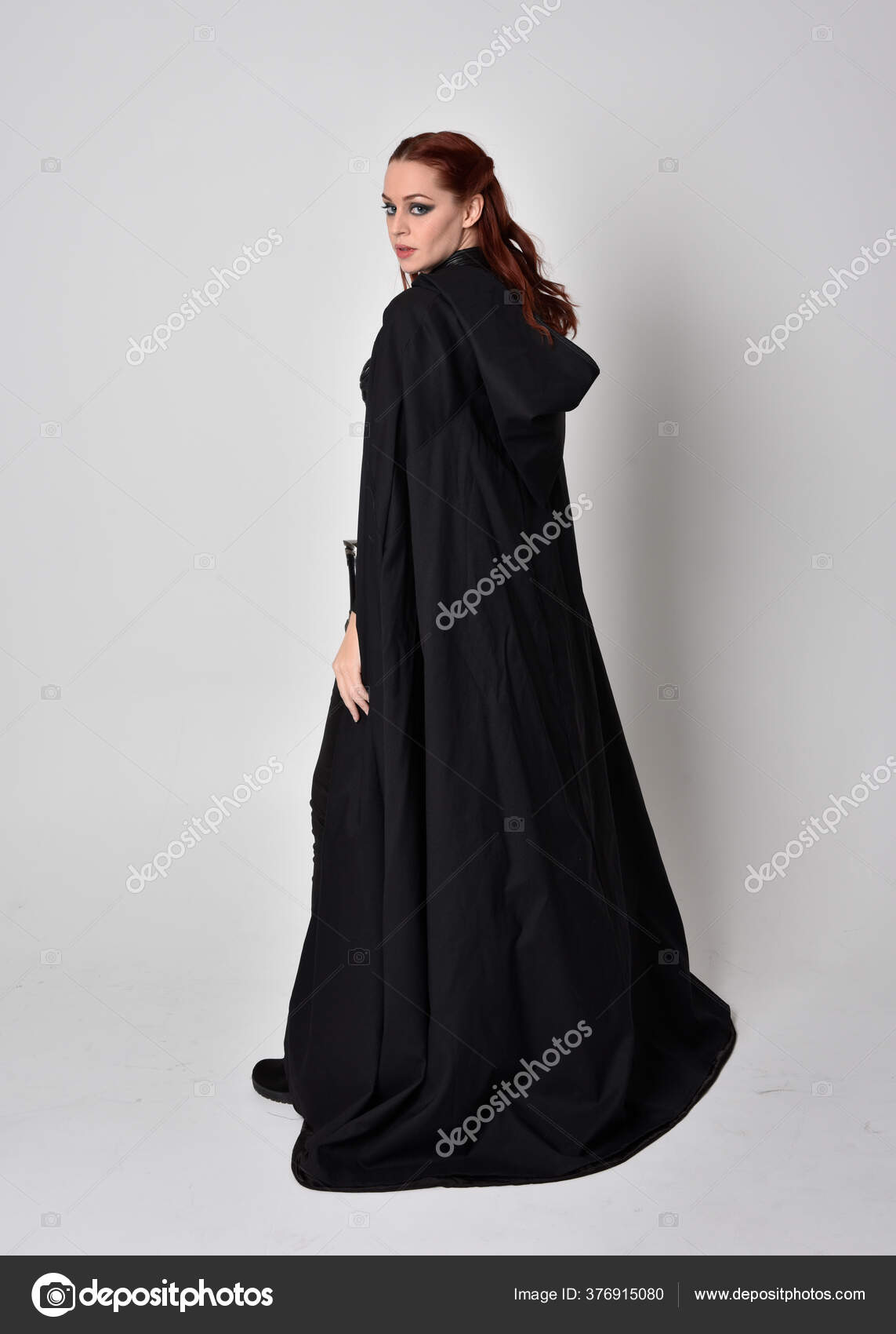 一个穿着黑色长斗篷的女人的幻想画像全长站立姿势背对着相机与工作室背景隔离 图库照片 C Faestock