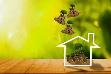 Ev ikonu ve kenevir torbası para ağacı üstte, tepeden düşüyor, bokeh doğa geçmişi, konsept para tasarrufu, yatırımlar, bankada finansal planlama, ev satın alma ve emlak ve sigorta yatırımları için