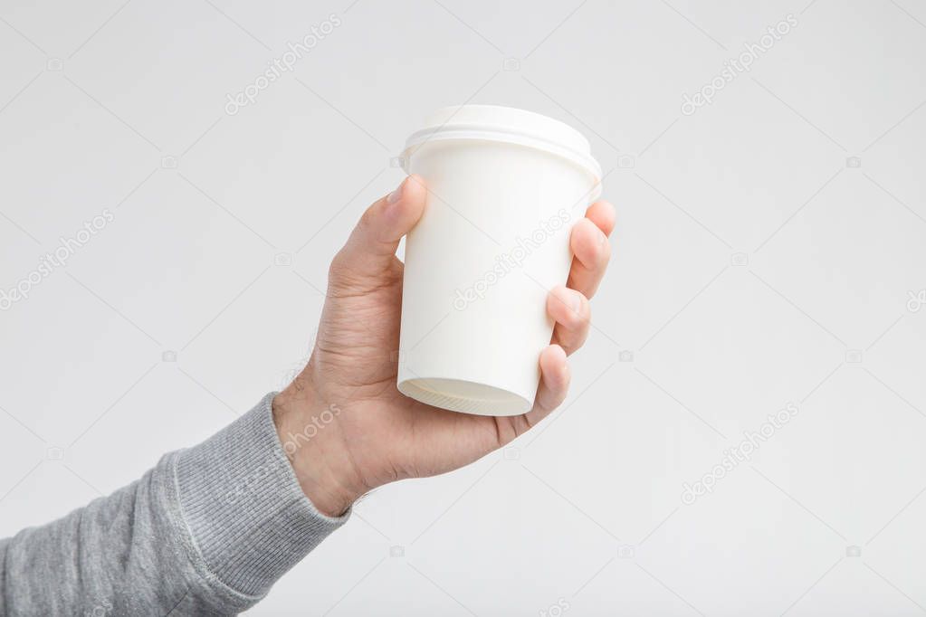 A paper cup of coffee in the hand. White paper cup of coffee in hand. For mock up. Isolated	