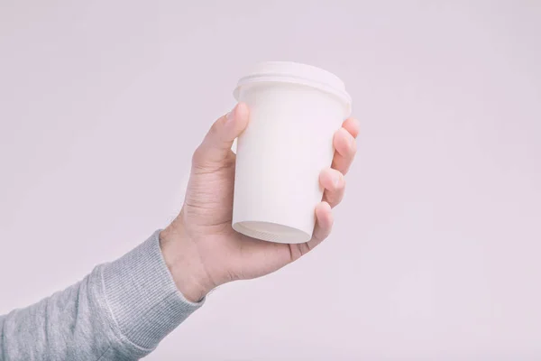 A paper cup of coffee in the hand. White paper cup of coffee in hand