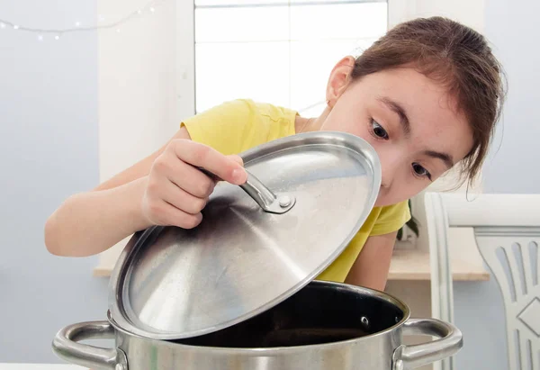 Girl peeks into the pan to find food — Stock Photo, Image