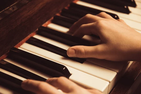 the hands on the piano keys. Photo piano in retro style.