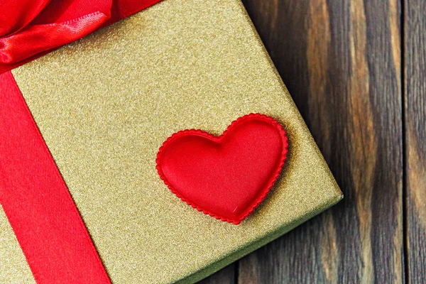 Подарочная коробка с красным луком и сердцем на деревянном фоне. подарок с любовью — стоковое фото