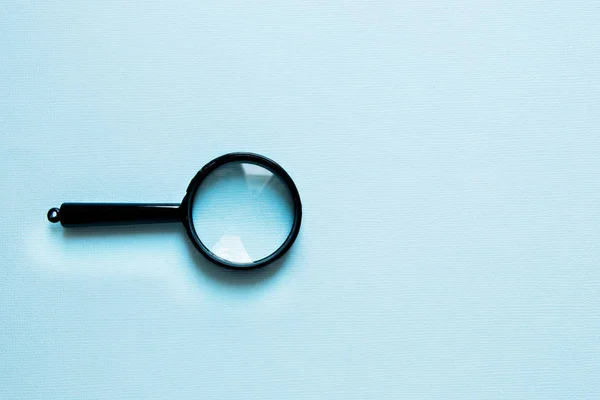 Black little Magnifier on a blue background — Stock Photo, Image