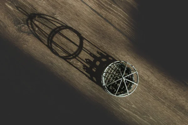 Pequena gaiola decorativa branca em um fundo de madeira e sombra a partir dele, a vista do topo — Fotografia de Stock