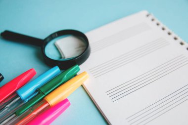 Renkli kalemler ve metin için bir not defteri beyaz bir kağıda Büyüteç. Eğitim ya da iş kavramı