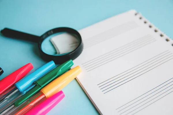 Lápices de colores y lupa en una hoja blanca de bloc de notas para text.Education o concepto de negocio — Foto de Stock