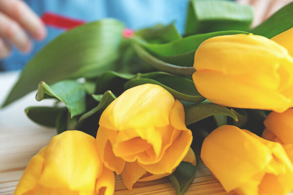 spring bouqet of yellow tulips on a white wooden background close up