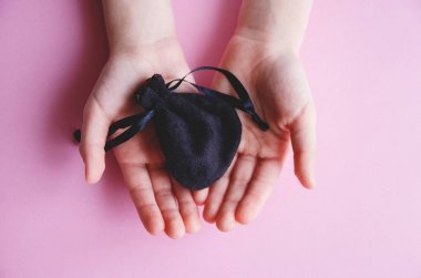 Kızın elini tutarak takı üzerinde pembe bir arka plan için bir küçük siyah çantası, küçük bir prenses için bir sürpriz