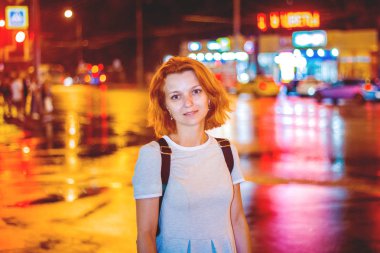 sevimli ateşli Kızıl saçlı kız gece şehirde ayakta ışıklar ve arabalar geçerken farlar ile yaktı
