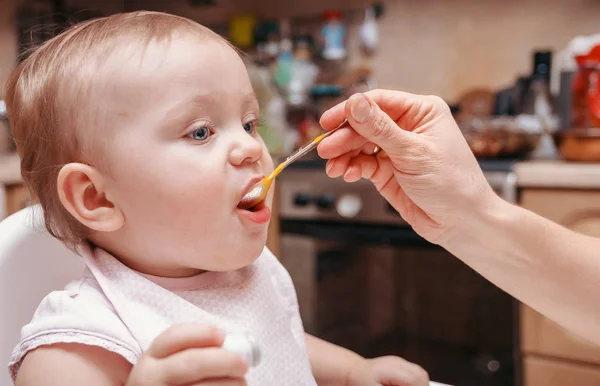 一个小可爱的女孩吃了一勺胡萝卜纯 — 图库照片