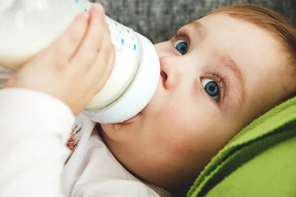 küçük mavi gözlü kız yatakta yatıyordu bir şişe süt içiyor