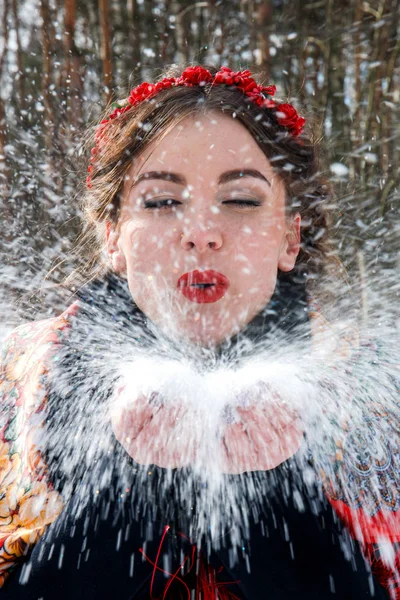 Dívka v červené rim fouká sníh z dlaní — Stock fotografie
