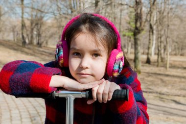 sıcak kulaklıklar bir scooter tekerlek üzerinde yaslanmış bir kız portresi