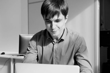 ofiste bir dizüstü bilgisayar önünde güleryüzlü biri siyah beyaz portre