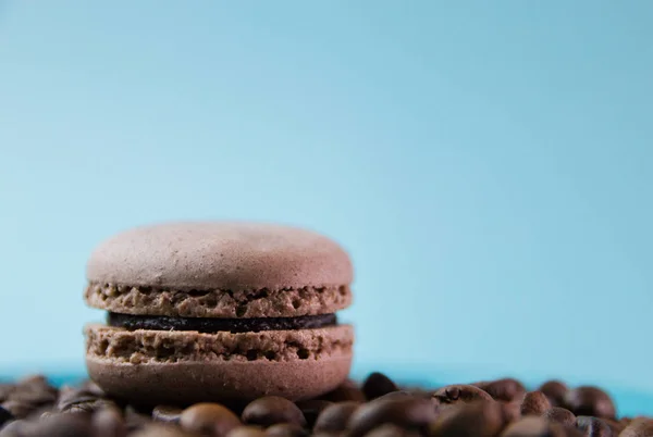 Μακαρόν σε τυρκουάζ φόντο με κόκκους καφέ, καφέ σοκολατένια αμυγδαλωτά, επιλεκτική εστίαση — Φωτογραφία Αρχείου