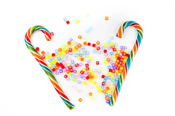 Colorful festive Lollipop and small cube letters on white background selective focus top view — Stock Photo, Image