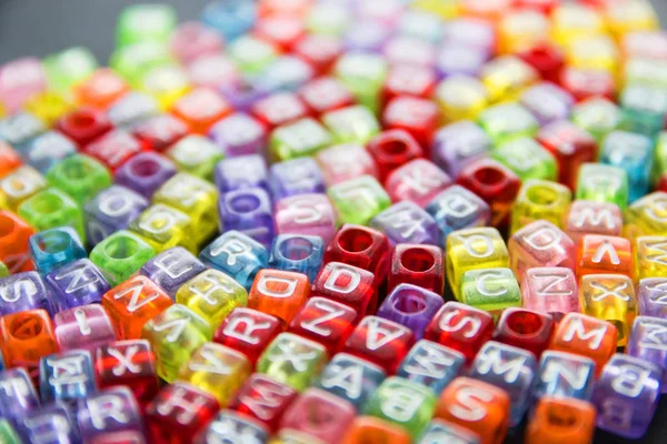 Un bouquet de petites lettres multicolores à la surface d'un fond sombre, mise au point sélective Photo De Stock