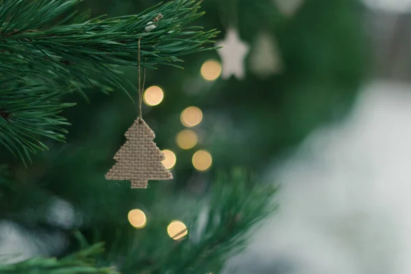 Luminoso sfondo natalizio festivo, albero di conifere decorato con semplici decorazioni natalizie con luce bokeh brillante dalla ghirlanda — Foto Stock