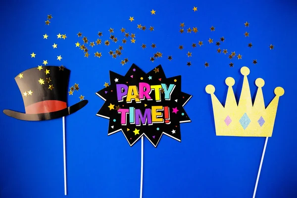 Party time, fun, flatlay overhead black paper photo stand props star hat crown and party blue background copy space — Stock Photo, Image