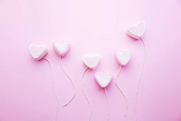 Pastel Valentine background is made of marshmallow souffle in the form of hearts on a string on a pink background. Valentine's day concept with copy space — Stock Photo, Image